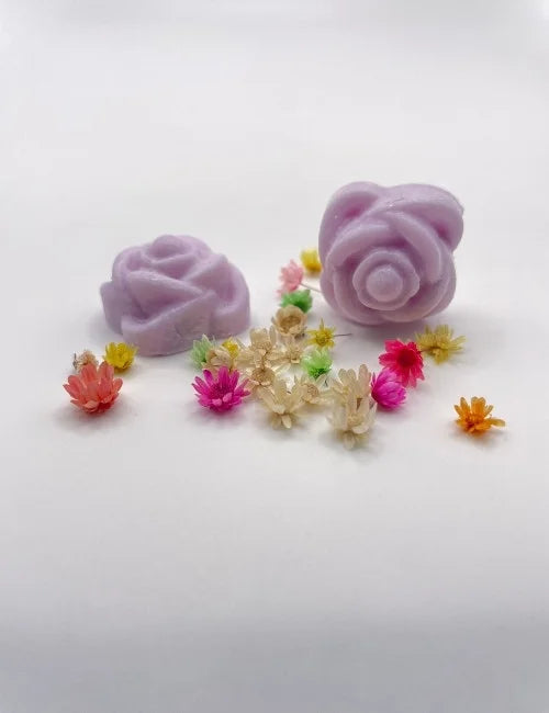 Lavender rose-shaped wax melts surrounded by colorful dried flowers.