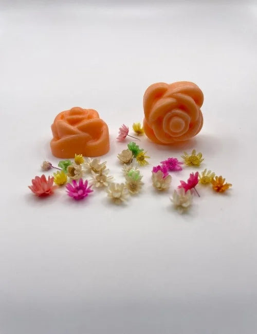 Orange rose-shaped wax melts surrounded by colorful dried flowers.