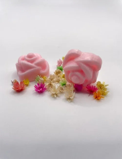 Pink rose-shaped wax melts surrounded by colorful dried flowers.