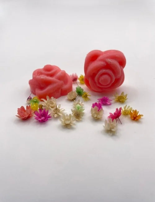 Red rose-shaped wax melts surrounded by colorful dried flowers.