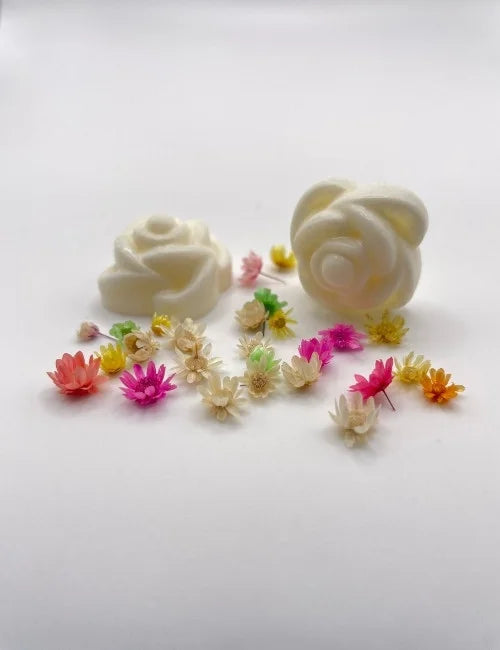 White rose-shaped wax melts surrounded by colorful dried flowers.